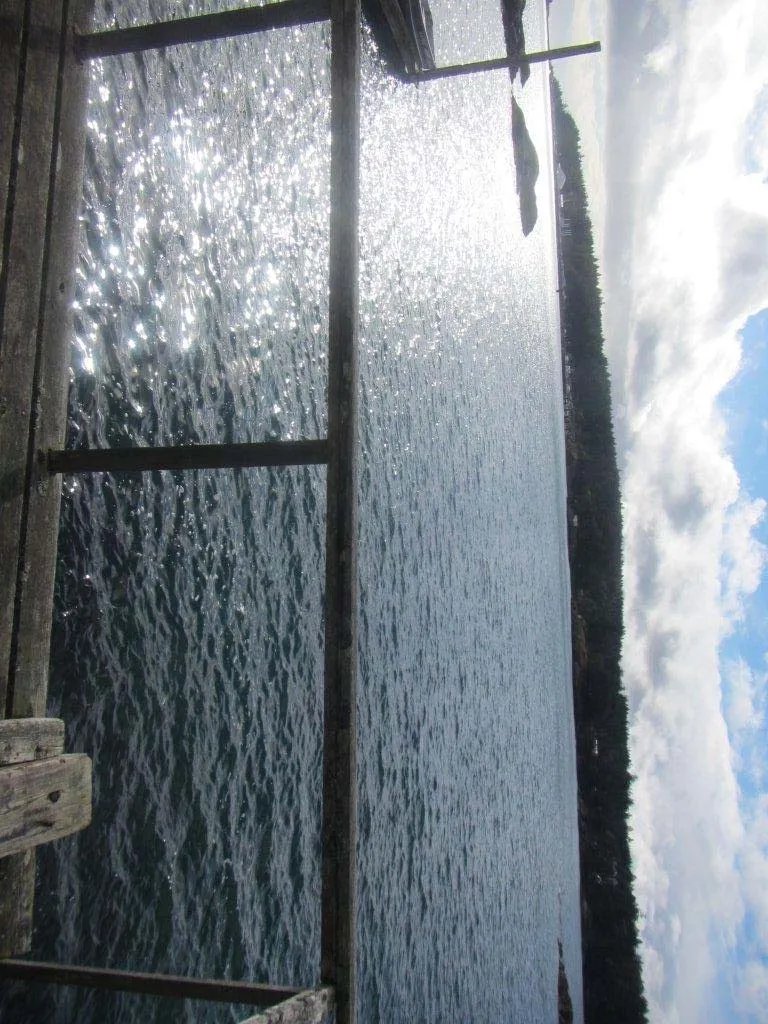 View of the water through the existing dock's wooden railing