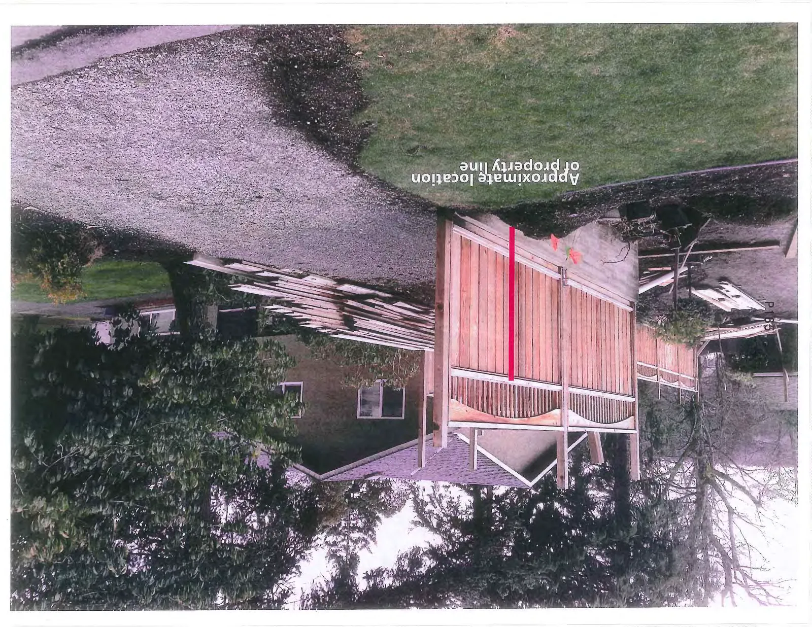 Photograph of a wooden fence under construction with a red line indicating the approximate location of the property line.