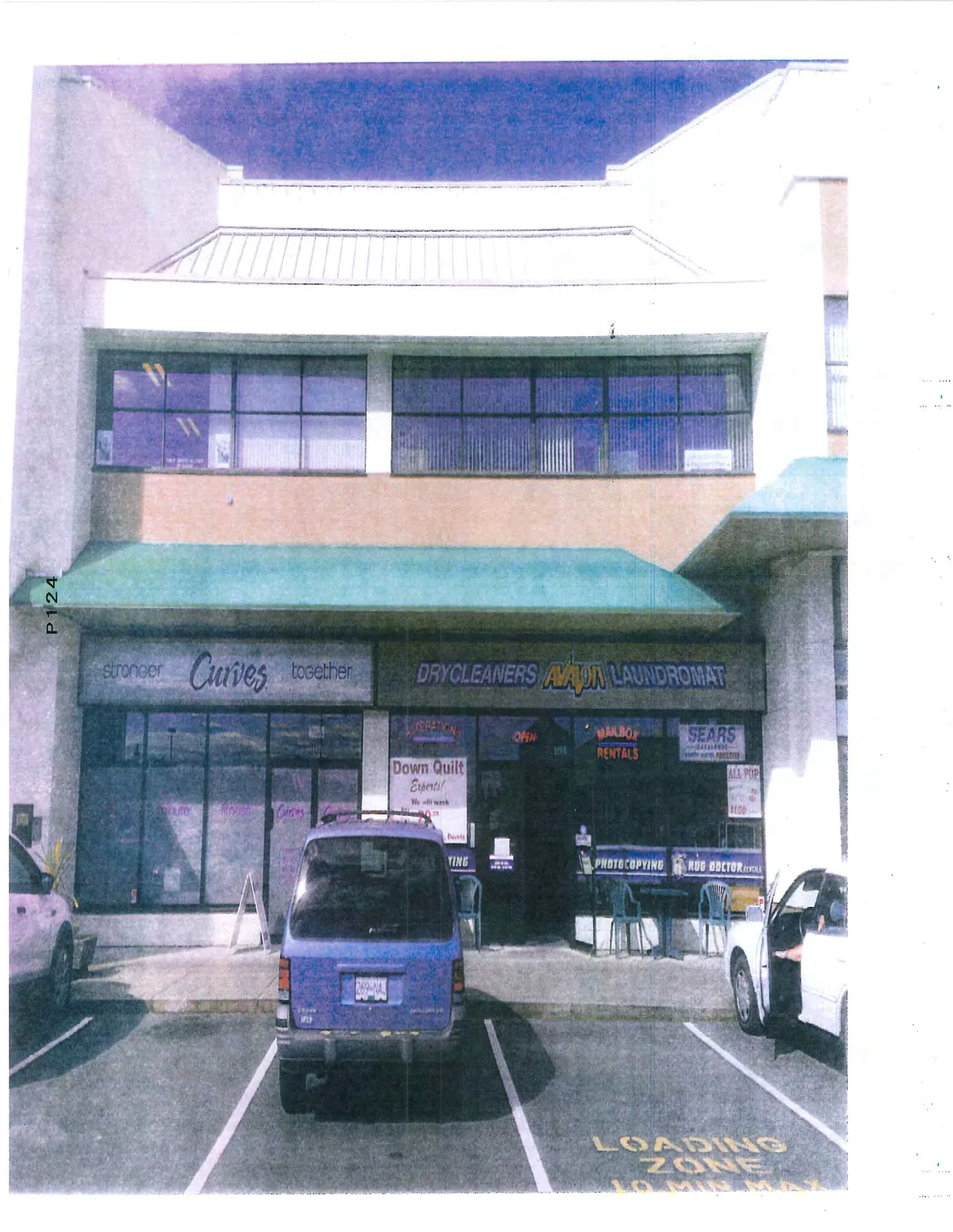 Wide-angle photograph of the shopping center storefronts including "Curves", "Avalon Laundromat", and "Sears", with a "LOADING ZONE 10 MIN MAX" area in the foreground.