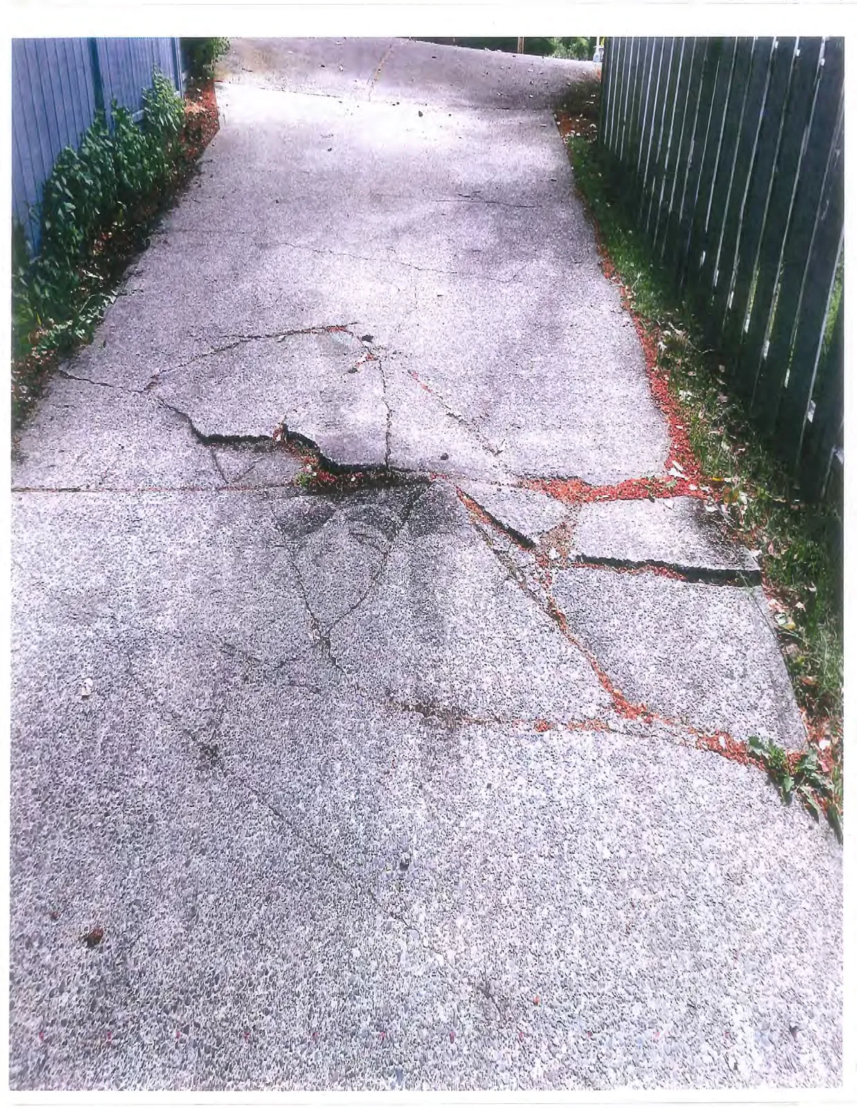 View of significant cracks and structural damage in an asphalt surface, likely a driveway or walkway.