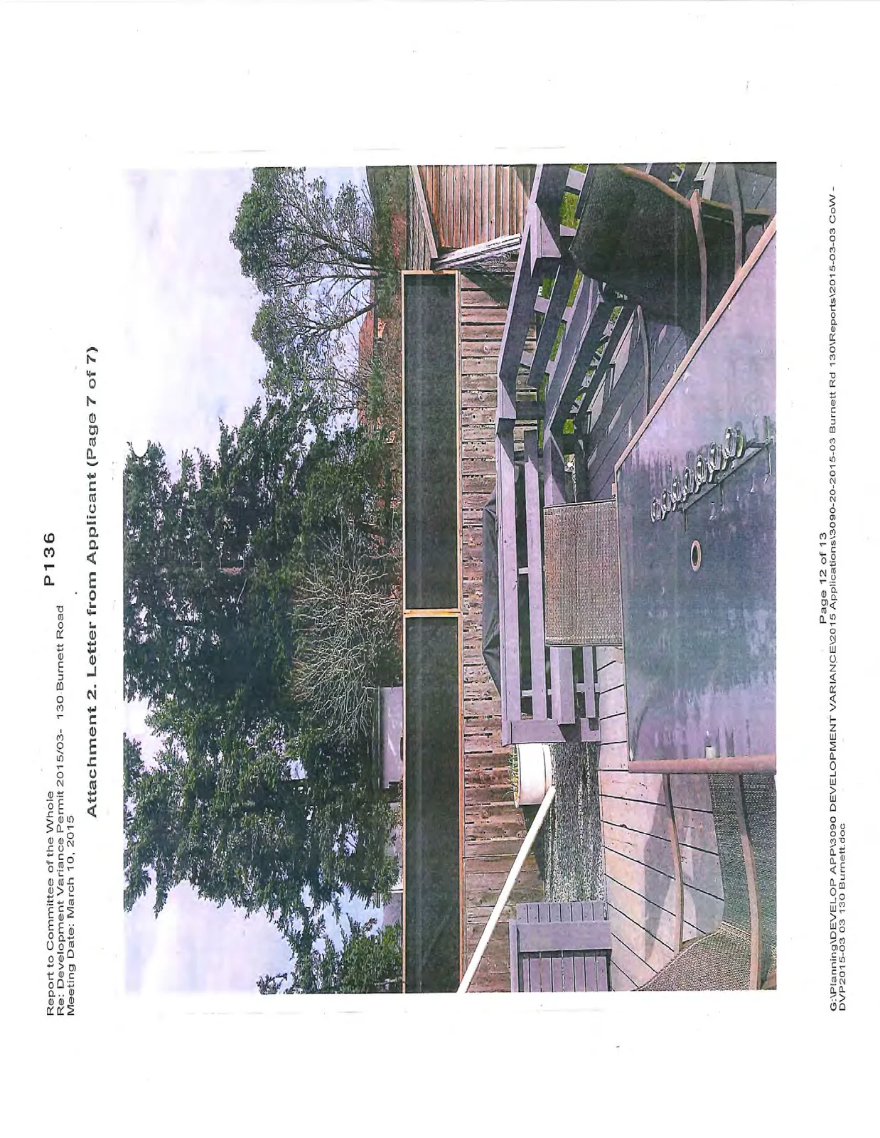 Photo of a wooden deck with an outdoor dining table, chairs, and a view of surrounding trees