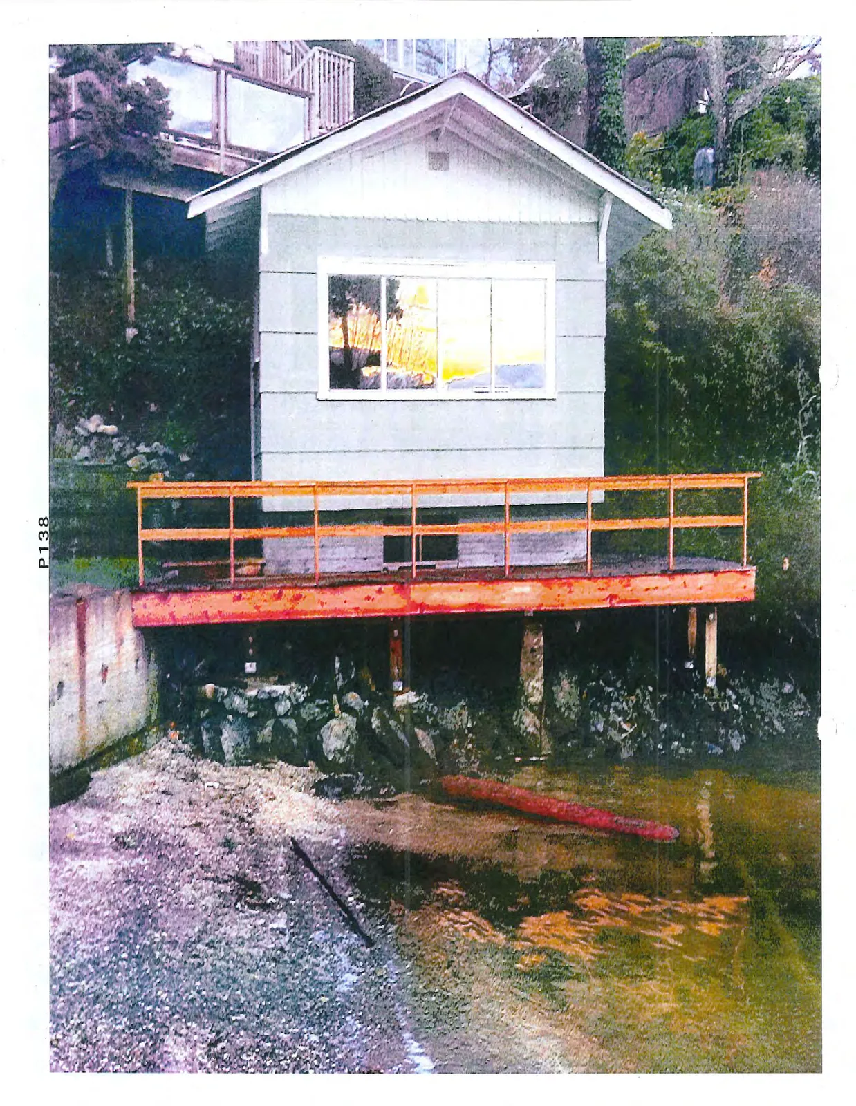 Exterior view of the same boathouse showing a newly constructed reddish-orange wooden deck and railing.