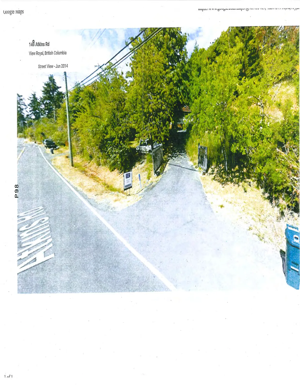 Street view photograph of the driveway entrance at 148 Atkins Rd, featuring a small sign, a wooden gate, and dense trees alongside the road.