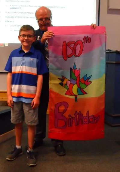 Student holding their winning banner design featuring a heart and maple leaf