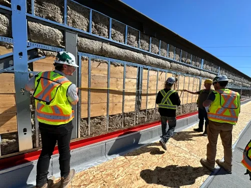 Photograph of construction crew working on the building envelope and wall cladding