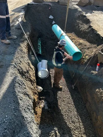 Worker installing upgraded drain pipe in trench at 7 Erskine Lane