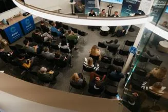 High-angle view of an audience attending a presentation in the COAST hub event space