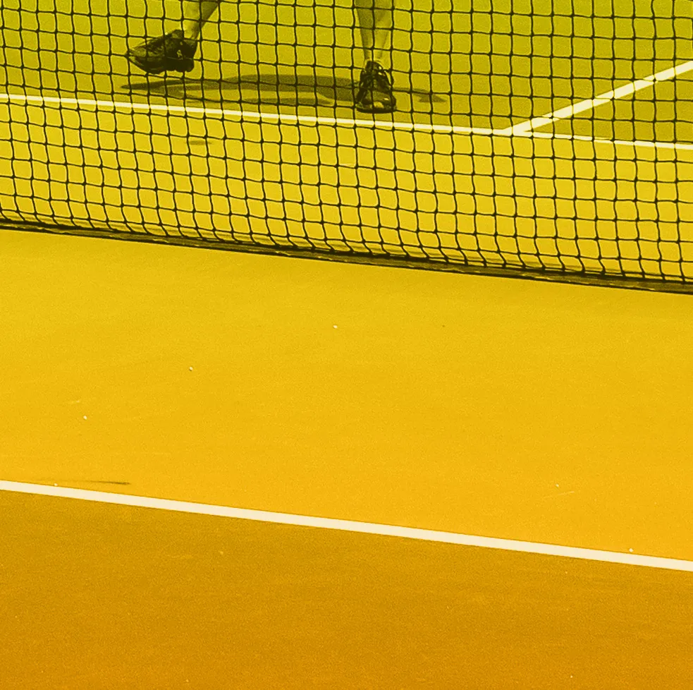 Close-up of player's legs in white skirt and athletic shoes on a sports court
