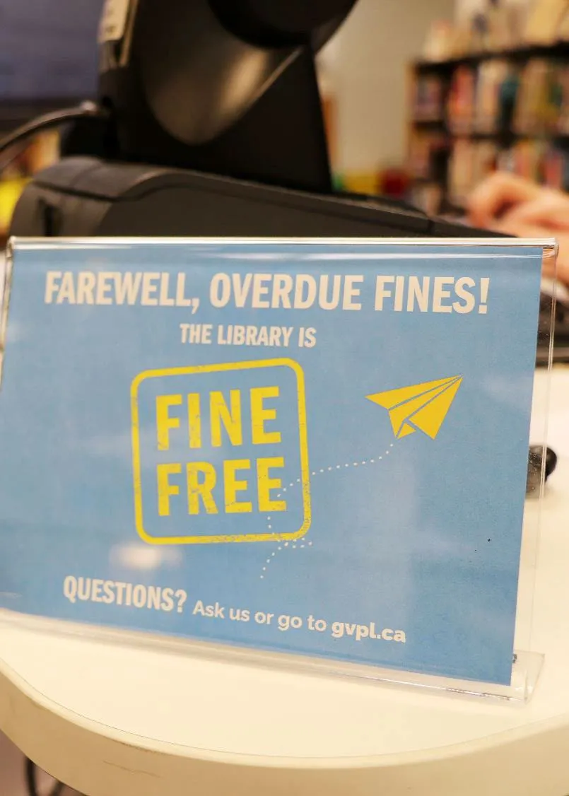 Photo of a sign at a library counter announcing "Farewell, Overdue Fines! The Library is Fine Free."