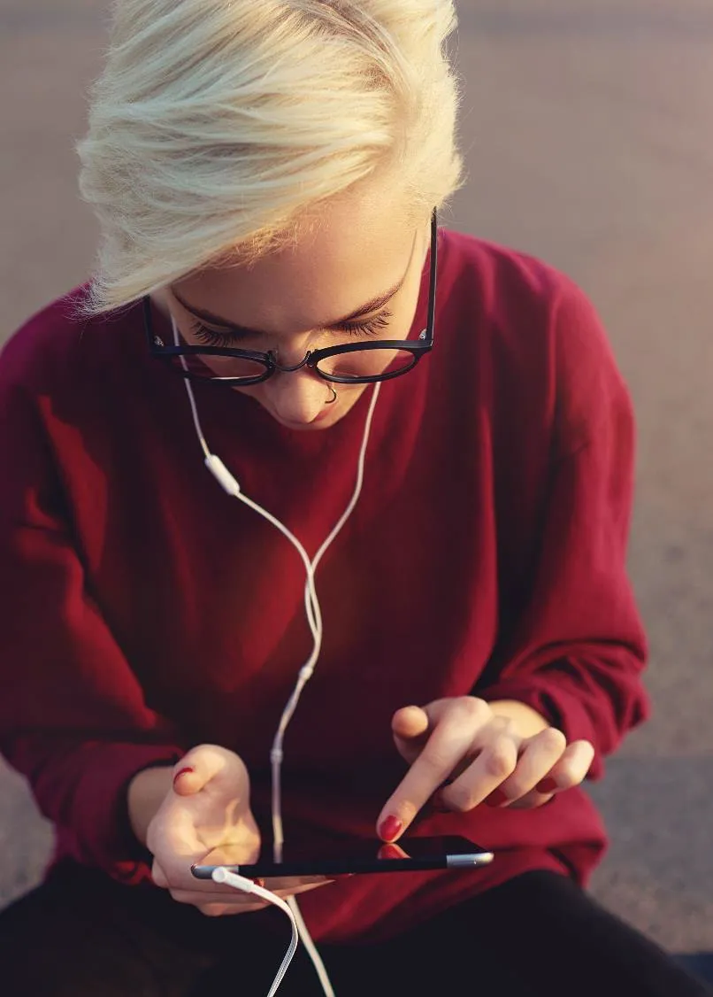 Photo of a person with headphones using a mobile device for digital engagement.