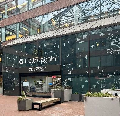 Photo of the exterior of the library building with bird decals and "Hello again!" on the windows.