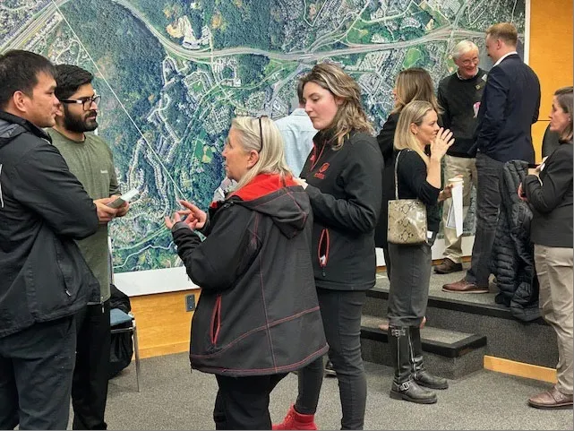 Attendees at the business mixer gathered in front of a large aerial map
