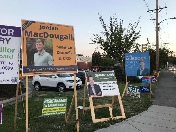Large wooden-frame election signs for Jordan MacDougall, Sasha Izard, and Dean Murdock