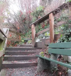 Green wooden bench located on a landing halfway down the staircase