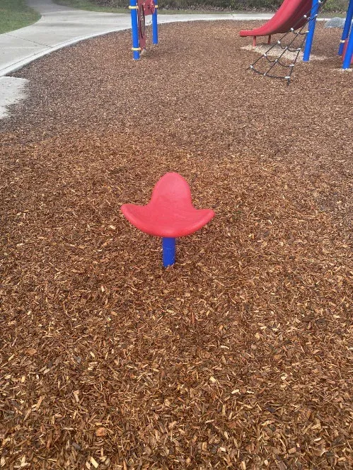 New red spinner playground equipment installed over woodchips at View Royal Park