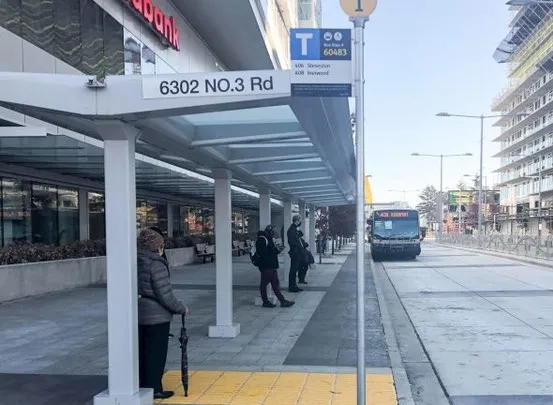 Passengers waiting at a modern glass-roofed RapidBus station at 6302 NO. 3 Rd