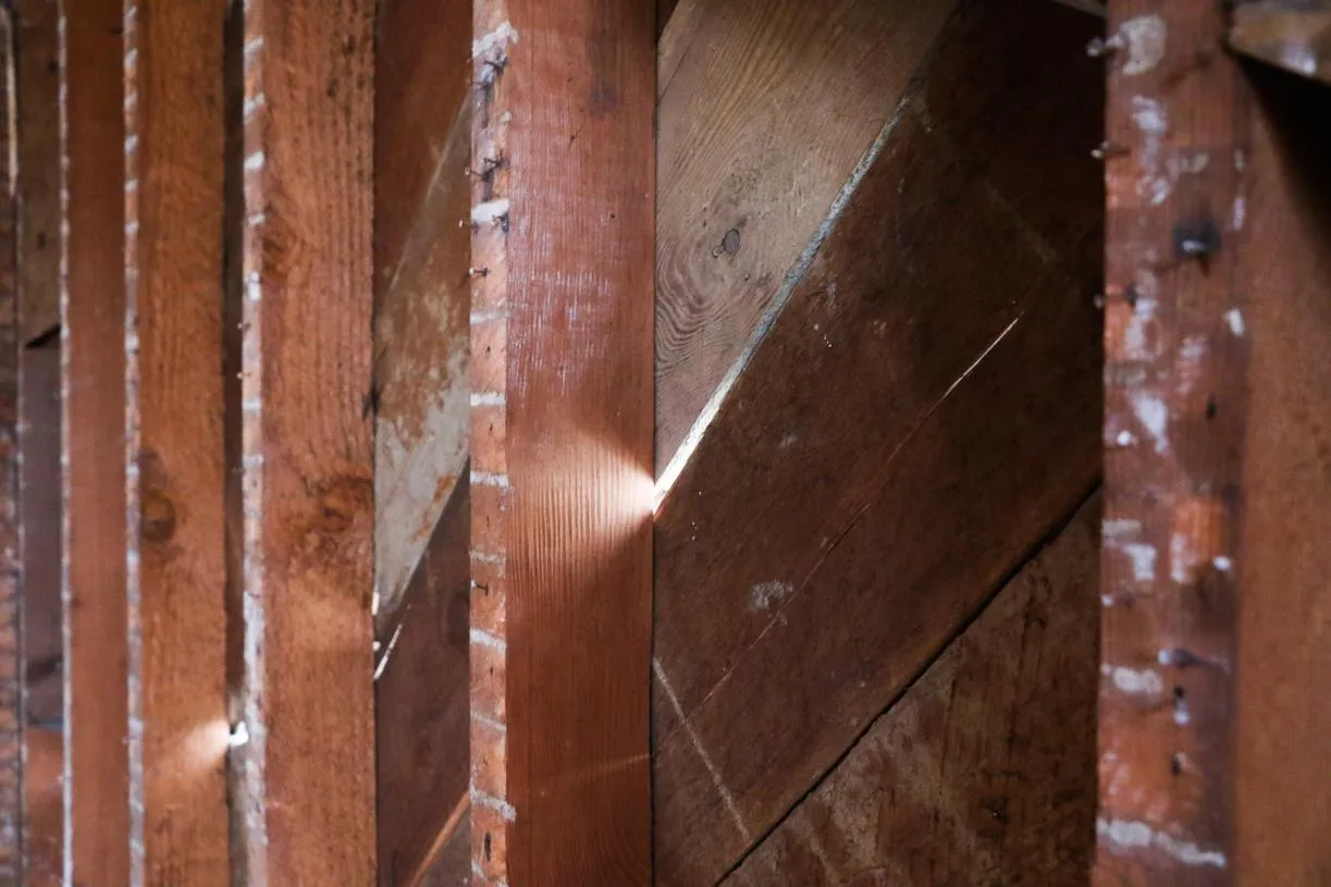 Exposed interior wall framing showing vertical studs and diagonal wood sheathing