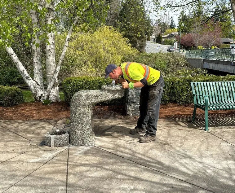 worker testing the newly replaced watering fountain