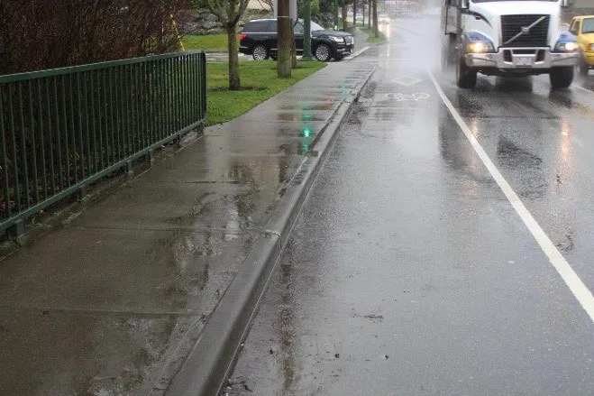 Rainwater pooling on the road and sidewalk at the southern approach to Parsons Bridge