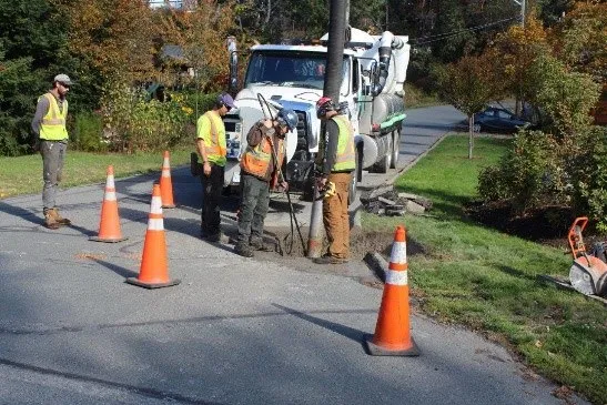 Crew working on a road with a white truck and orange cones