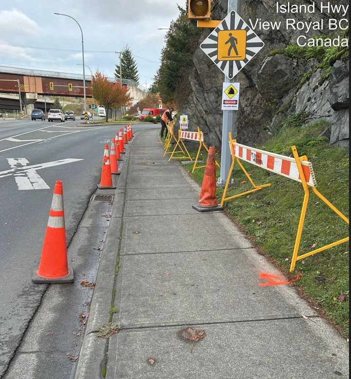 Sidewalk on Island Highway blocked by orange cones and barricades due to a falling rock hazard