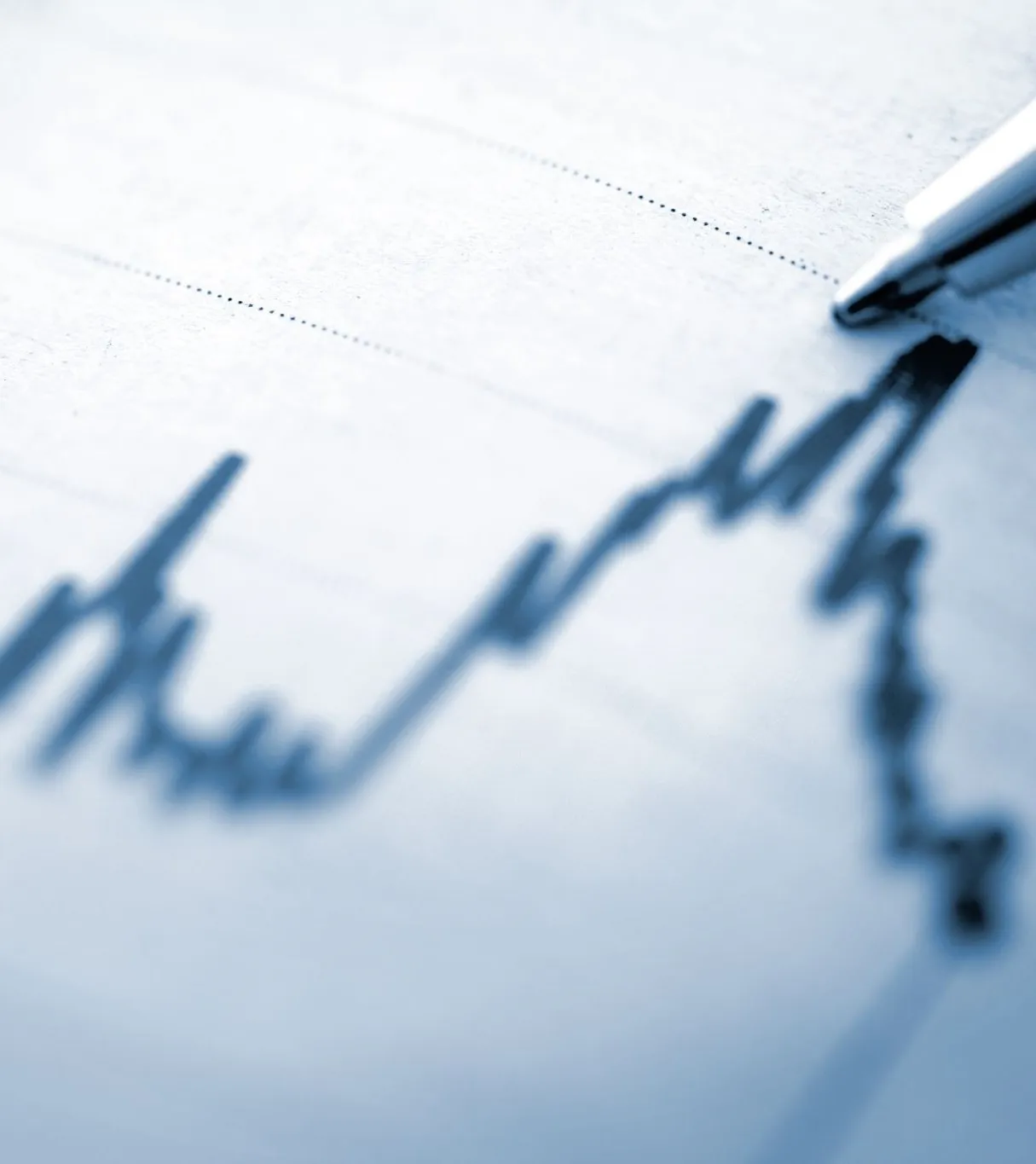 a pen pointing at a line graph on paper