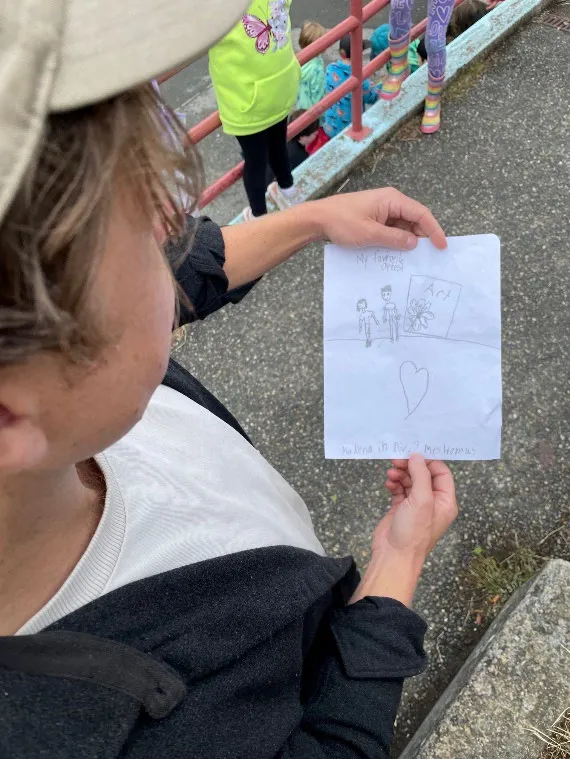 Mural artist, Collin Elder, receives art from a student at View Royal Elementary School