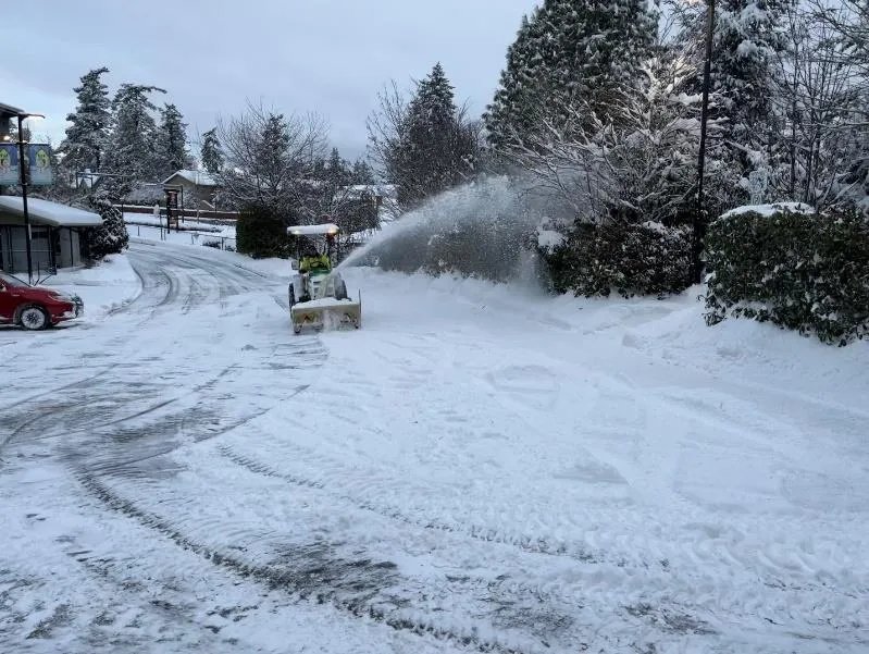 Parks staff using a snowblower in the parking lot