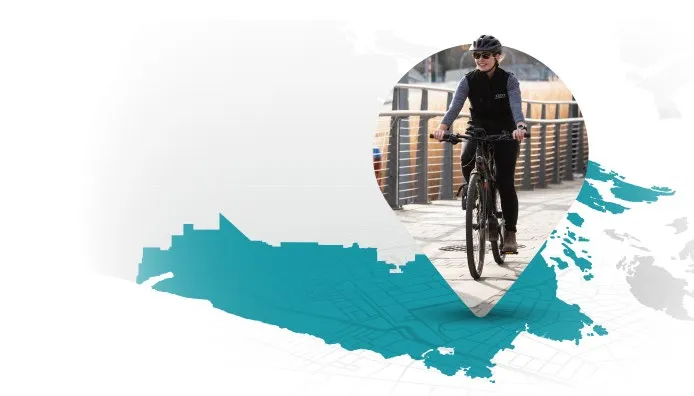 A woman riding a bicycle on a path, positioned inside a location pin over a teal map of the region