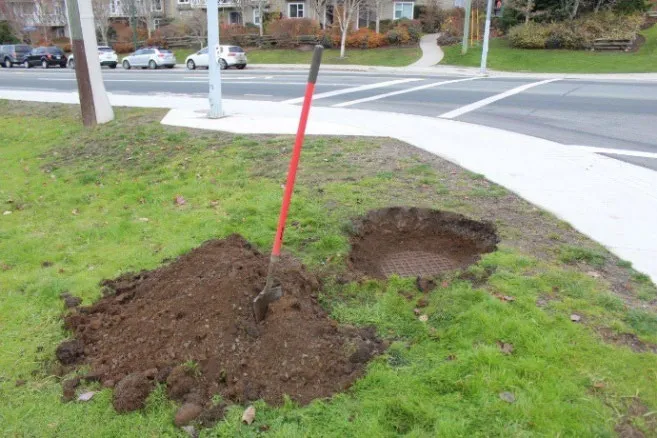 Photo showing a dirt pile and shovel where a buried sewer manhole was uncovered