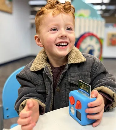Young boy smiling while using a Yoto screen-free audio player