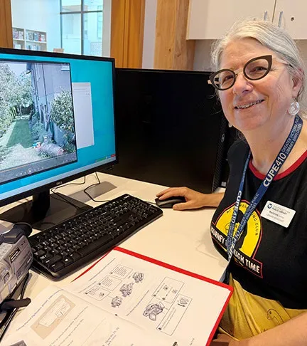 Library staff member sitting at a computer station next to a digitization device