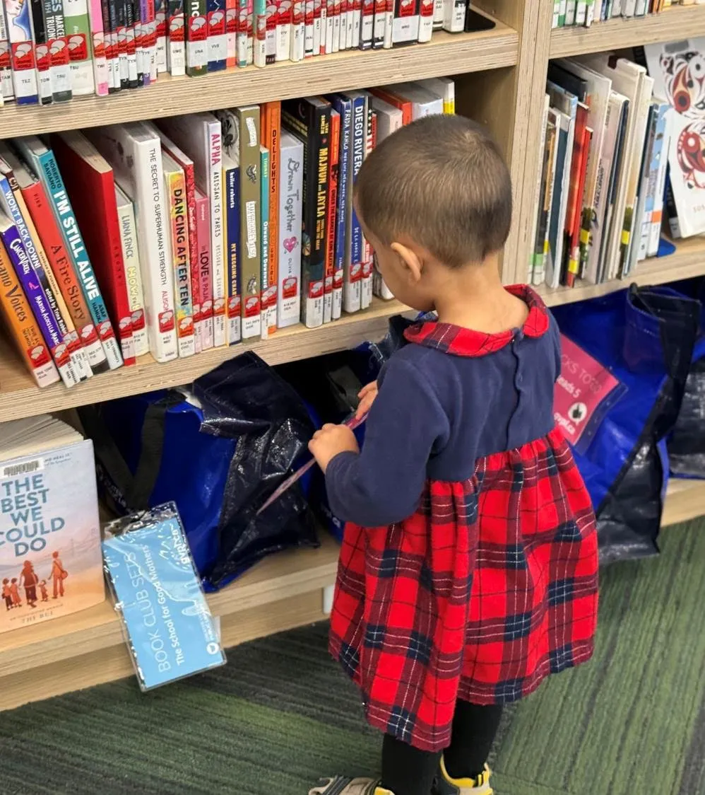 Child looking at books on a library shelf