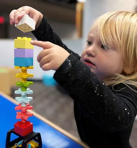 Child building a tower with colorful toy blocks