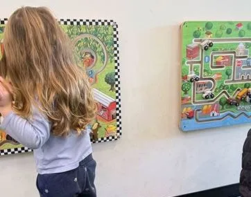 Young girl looking at interactive sensory panels on a library wall
