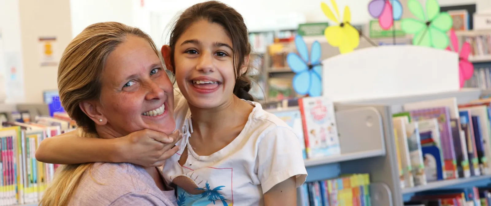 Mother and young daughter smiling and hugging in a library