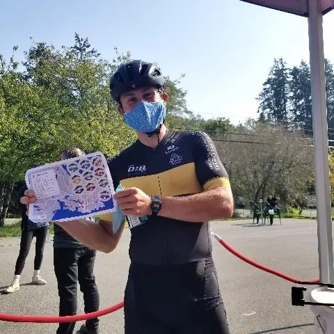A cyclist in a jersey and mask holding an event passport map