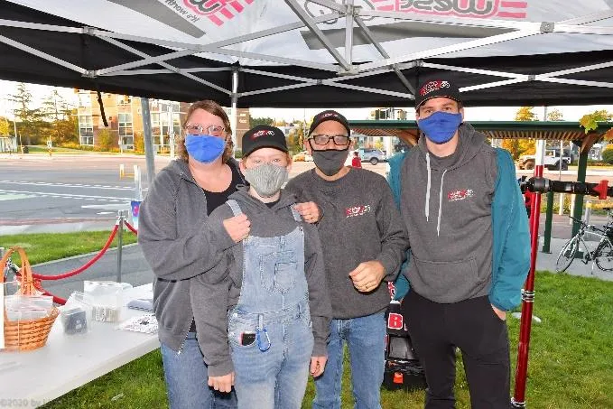 A group of four event participants wearing masks under a tent