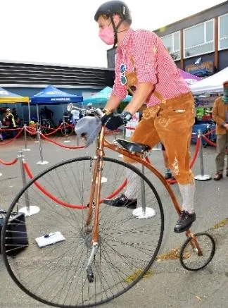 A person standing next to a large-wheel penny farthing bicycle