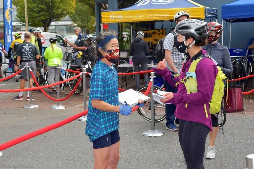 Two cyclists in event-related apparel posing at a station
