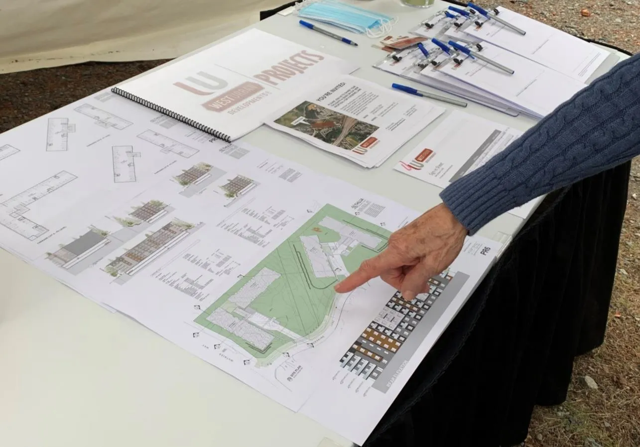 Photo of a presentation table featuring project site plans, informational brochures, and materials