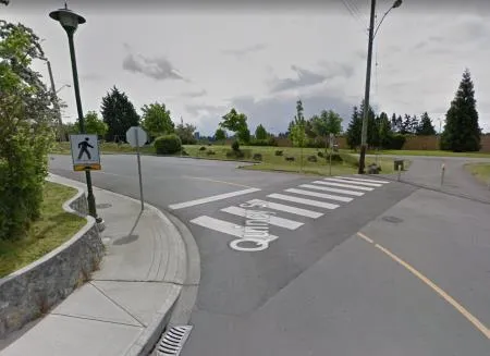 A raised crosswalk on a speed table at a road intersection with pedestrian crossing signs.