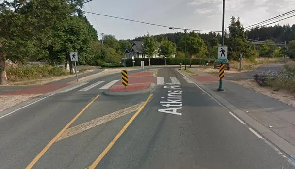 A long raised median barrier along the center of a roadway in front of a multi-story building.