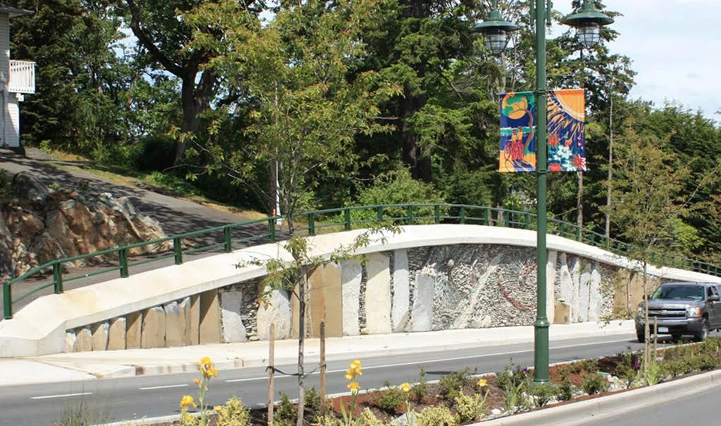 Stone retaining wall art installation with street lamps and decorative banners