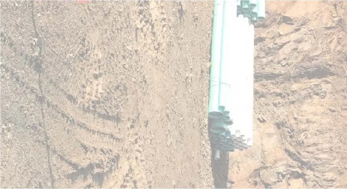 Site photograph fragment showing ground area with piping