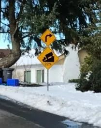 Photograph of a physical road sign in a snowy environment showing a curve and 22% grade warning