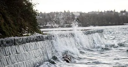 Photograph of waves crashing over a stone sea wall