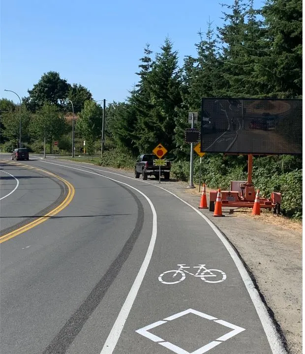 View of a curved road with a bicycle lane marker and a portable digital message board