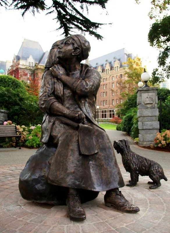 Bronze sculpture of Emily Carr sitting on a rock with a small dog nearby