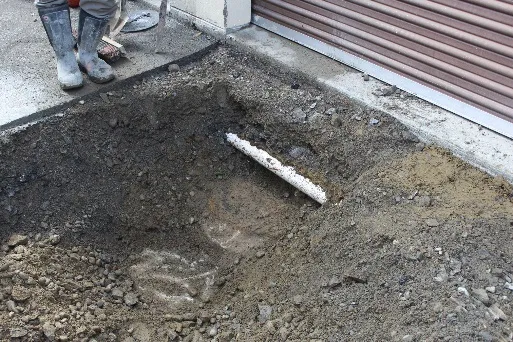 Buried sewer manhole up against storage building foundation with perimeter drain